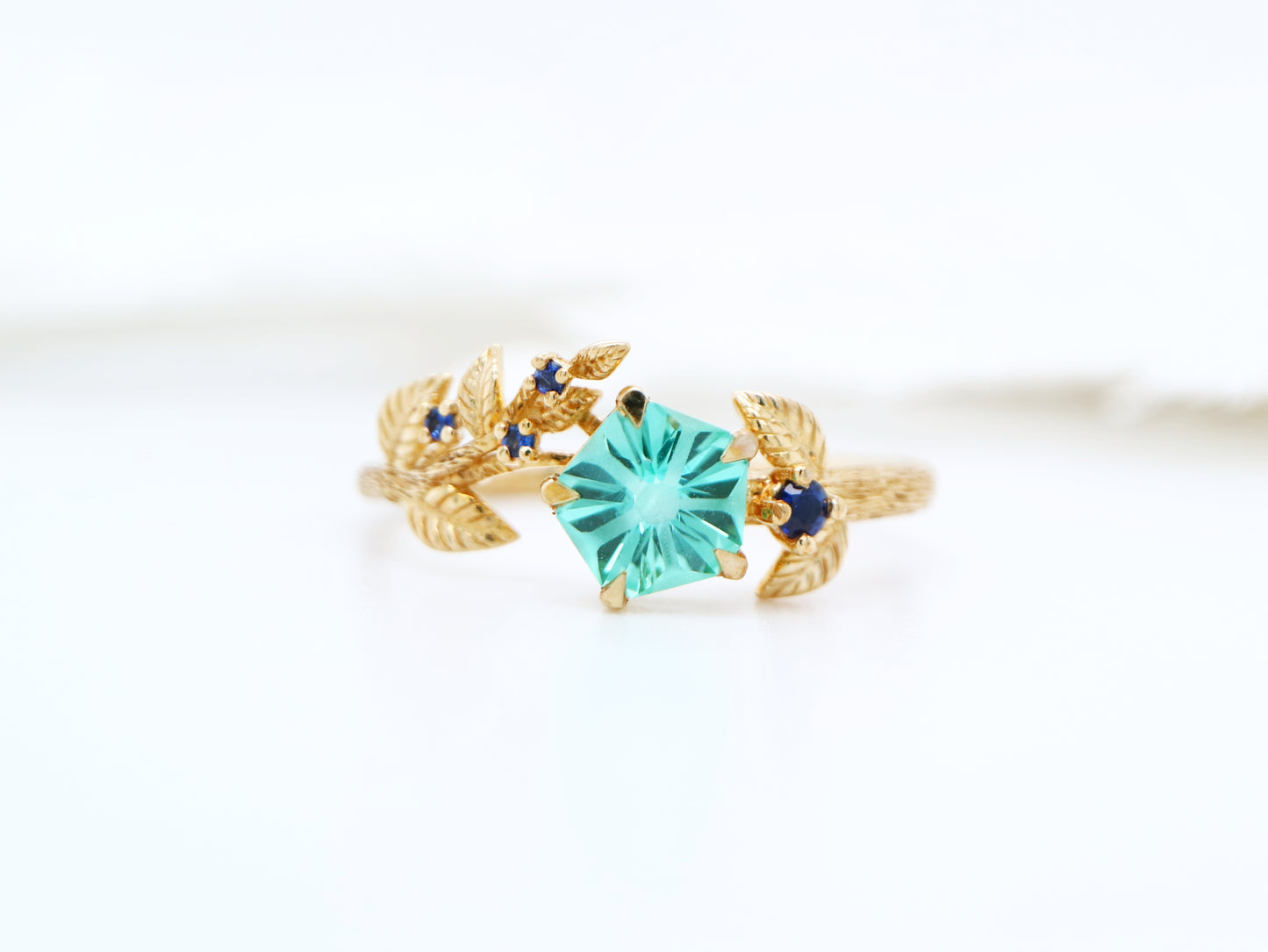 Teal sapphire Hanami ring set in golden leaf and twig design